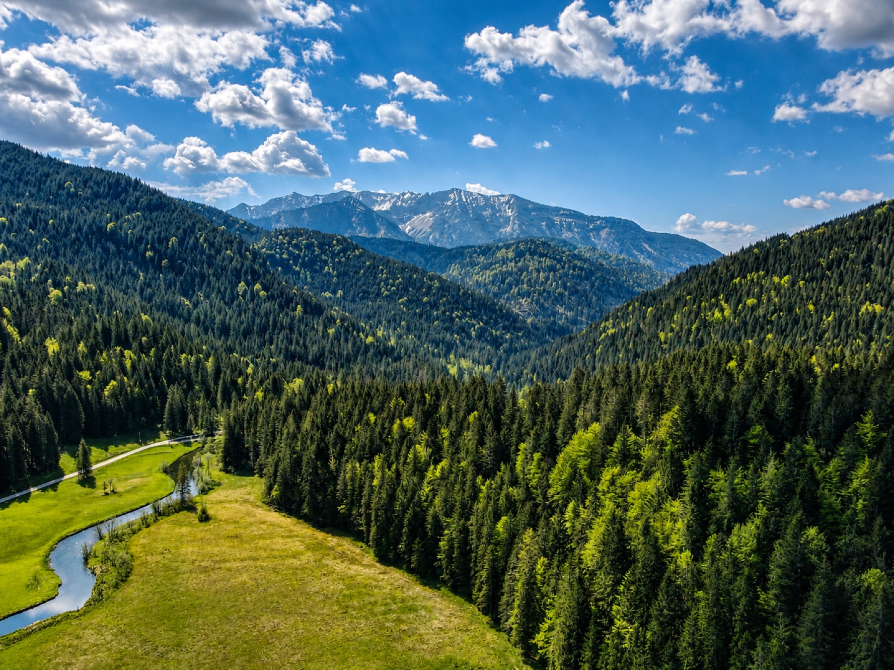 Rolling gravel road across a high alpine plateau, Julian Alps in the distance